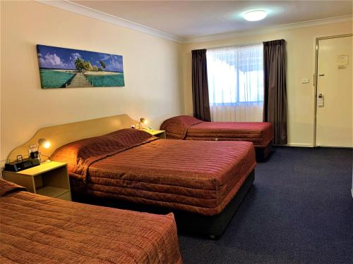 a hotel room with two beds and a window at Silo Motor Inn Biloela in Biloela