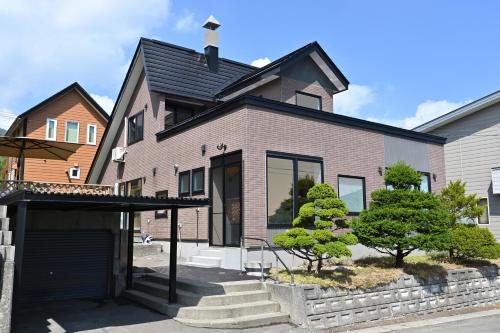 a brick house with a black roof at Casi 15 in Furano