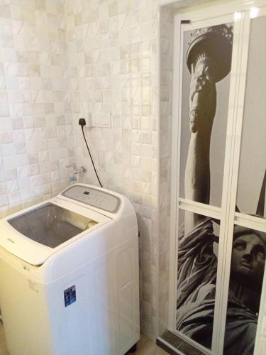 a washing machine in a bathroom with a picture of a woman at Fastbook Sun Moon City Home 12Pax in Ayer Itam