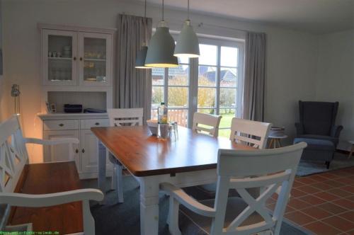 uma cozinha e sala de jantar com uma mesa de madeira e cadeiras em Hüs Neiwoi em Borgsum