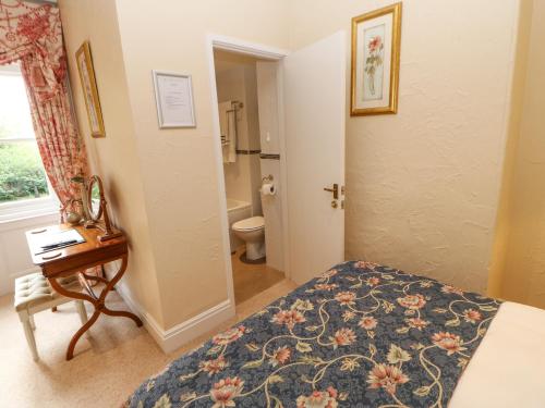 a bedroom with a bed and a desk and a bathroom at Horsley Hall in Eastgate