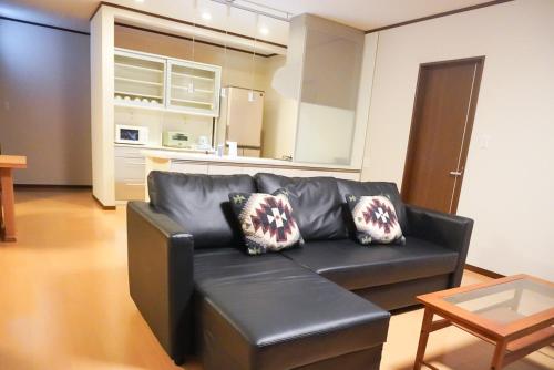 a living room with a black leather couch and a table at Tiz wan 中田あわじ in Awaji