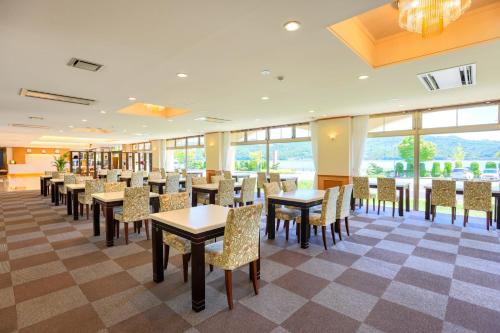 a dining room with tables and chairs and windows at Fuji Matsuzono Hotel in Yamanakako
