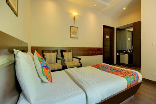 a bedroom with a bed and a chair at FabHotel Phoenix Hospitality Near DLF Cyber Hub & Metro, Gurugram in Gurgaon