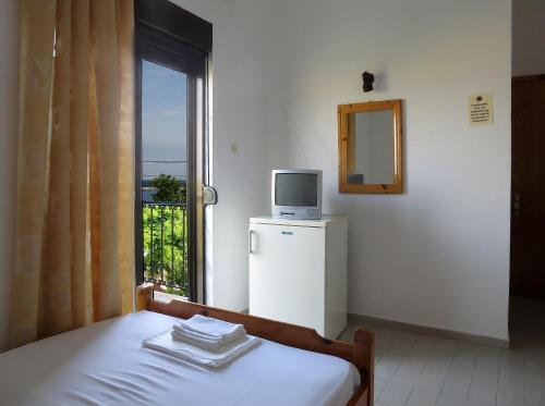 a bedroom with a bed and a television on top of a refrigerator at Thanasis Matsas Rooms in Kamariotissa