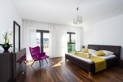 a bedroom with a large bed and a purple chair at Luxury City Villa Trogir in Trogir