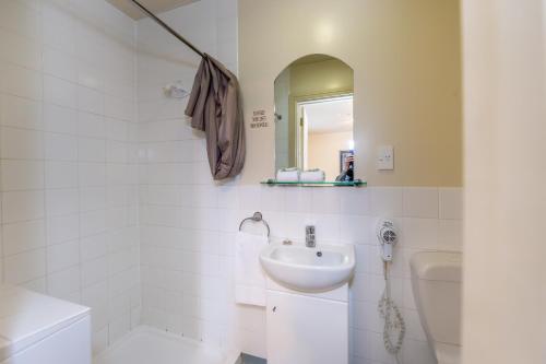Baño blanco con lavabo y aseo en The Grand Hotel & Bar - Akaroa, en Akaroa