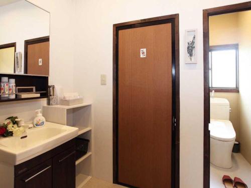 a bathroom with a sink and a toilet and a door at Guest House Zen in Yamanakako
