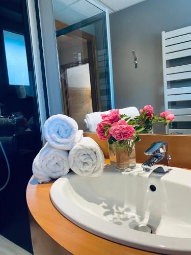 a bathroom sink with towels and a vase of flowers at Les Reflets du Lac in Gérardmer