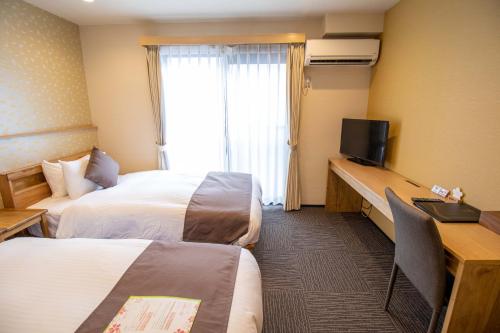 a hotel room with two beds and a flat screen tv at Stay SAKURA Kyoto Shijo Karasuma in Kyoto