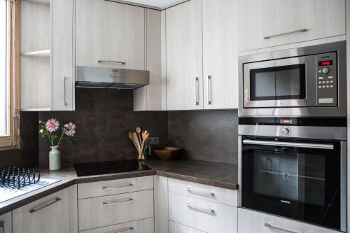 une cuisine avec des armoires blanches et un micro-ondes dans l'établissement Le Beausite C Apartment - Chamonix All Year, à Chamonix-Mont-Blanc