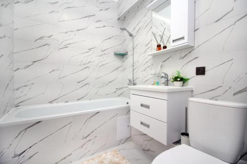 a bathroom with white marble walls and a tub and sink at New and cozy studio in the best area! 4 in Almaty