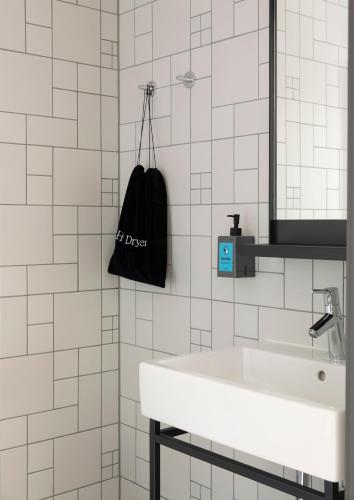 a white bathroom with a sink and a black bag at Comfort Hotel Xpress Youngstorget in Oslo