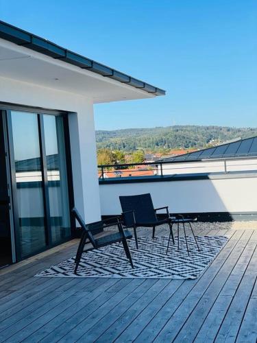 a deck with two chairs and a table on a building at Motel Inn Simbach in Simbach am Inn