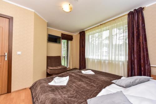 a hotel room with a bed with towels on it at Svečių namai Banga in Paplatelė