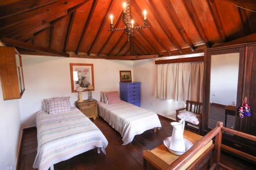 a bedroom with two beds and a chandelier at La Ventana del Bentayga in Tejeda