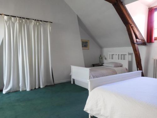 a bedroom with two beds and a white curtain at Maison de Marie in Pont-Sainte-Maxence