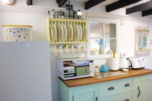 a kitchen with a counter with a microwave and a refrigerator at Romantic* Castle on the Hill Cottage *Framlingham in Framlingham