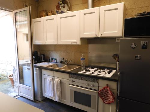 La cuisine est équipée de placards blancs, d'une cuisinière et d'un évier. dans l'établissement Maison de Marie, à Pont-Sainte-Maxence