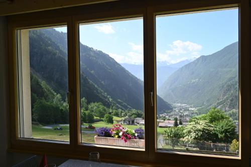 a window with a view of a valley with mountains at Agriturismo Miravalle in Brusio