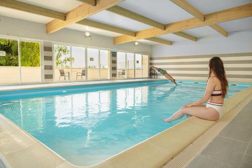 uma mulher sentada à beira de uma piscina em Kyriad Sens em Sens