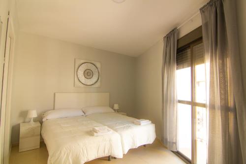 a bedroom with a white bed and a window at Apartamento Jerez in Jerez de la Frontera