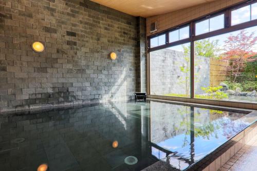 an indoor swimming pool with a brick wall and windows at Fuji Matsuzono Hotel in Yamanakako