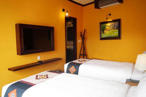 a room with two beds and a flat screen tv at Cat Cat Galerie d’Art in Sa Pa