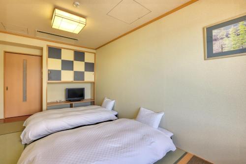 a bedroom with a bed and a tv at Fuji Matsuzono Hotel in Yamanakako