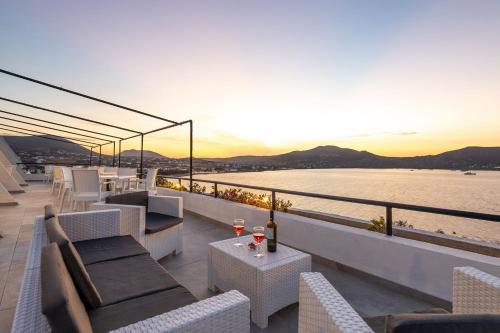 a balcony with couches and tables and a view of the water at Hippocampus Hotel in Naousa