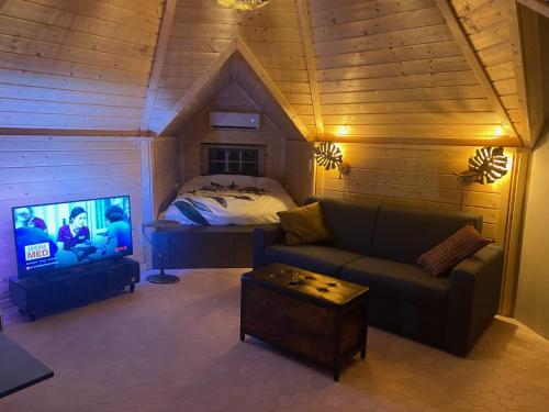 een woonkamer met een bank en een bed bij Luxe Finse Kota met Jacuzzi en SaunaBarrel de Zandhoef in Eersel