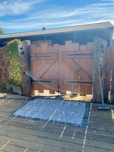 a building with a wooden fence next to a wooden deck at Luxe Finse Kota met Jacuzzi en SaunaBarrel de Zandhoef in Eersel