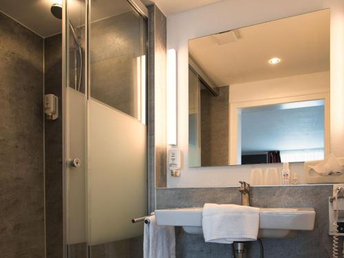 ein Bad mit einem Waschbecken und einem Spiegel in der Unterkunft Hotel Holländer Hof in Meschede