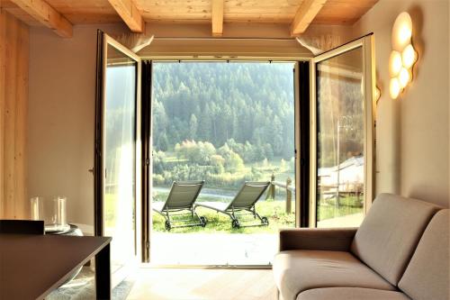 a living room with two chairs and a large window at Miki's Home - 2 bagni e giardino privato in Ponte di Legno
