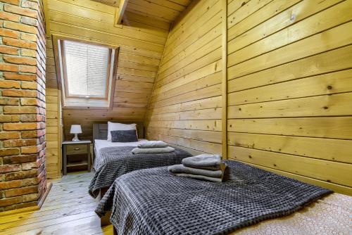 two beds in a room with wooden walls at Oaza Mazurska - Domek z kominkiem in Piecki