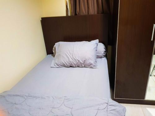 1 cama con sábanas blancas y almohadas en una habitación en Aloha Guest House 2 - Female Only, en Tangerang