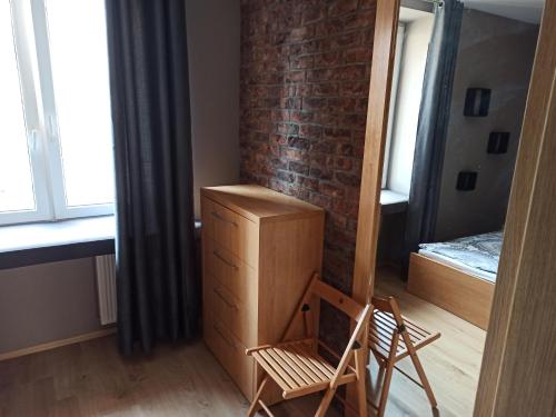 a bedroom with a brick wall and a dresser and a chair at Nordic Apartamenty Sienkiewicza in Białystok