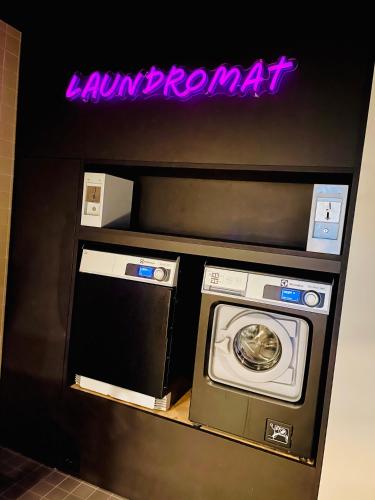 a washer and dryer in a room with a neon sign at Comfort Hotel Xpress Youngstorget in Oslo