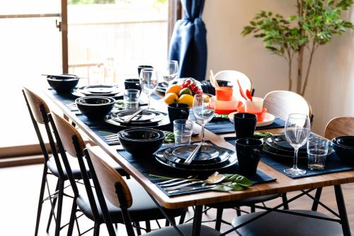 a table with black plates and wine glasses on it at Wave House Kujukuri Shimokaizuka Beachside - Self Check-In Only in Kujukuri