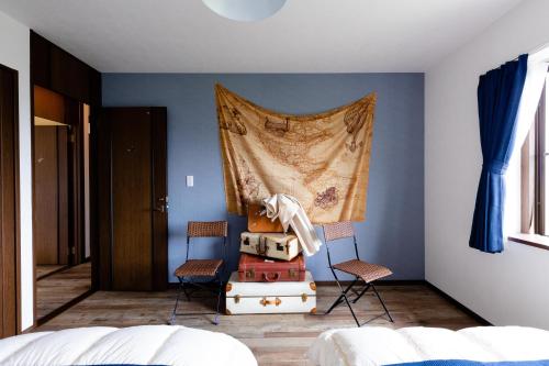 a bedroom with two chairs and a curtain on the wall at Wave House Kujukuri Shimokaizuka Beachside - Self Check-In Only in Kujukuri