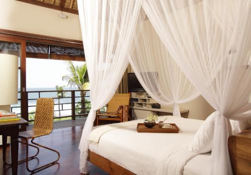 a bedroom with a bed with white curtains and a desk at Villa Melissa in Canggu
