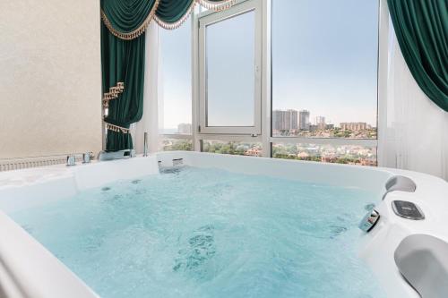 a large bath tub in a room with a window at Apart Hotel D'Monica in Odesa