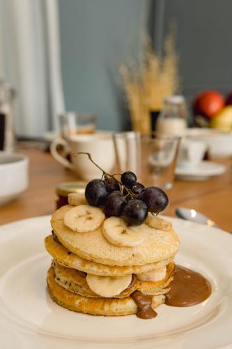 a stack of pancakes with bananas and grapes on a plate at NAIADES the residence ioannina castle in Ioannina