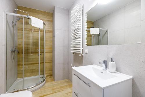 a white bathroom with a sink and a shower at Balticus Apartamenty Deluxe Promenada Gwiazd 14 in Międzyzdroje