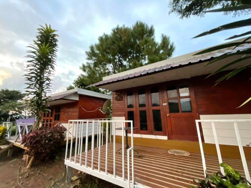 a house with a wooden deck in front of it at ภูน้ำทิพย์ รีสอร์ท in Ban Huai Phai