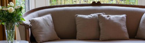 a couch with three pillows and a vase of flowers at Les Terrasses des Falizes B&B in Rochefort