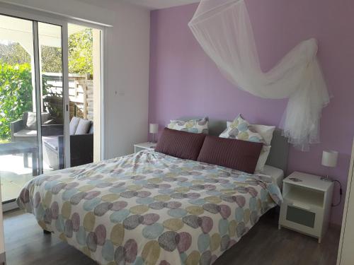 a bedroom with a bed with purple walls and a window at La Maison du Sommeil in Loubès-Bernac