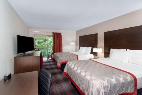 a hotel room with two beds and a flat screen tv at Ramada by Wyndham Maggie Valley in Maggie Valley