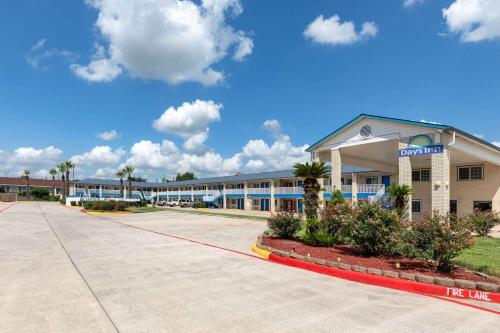 a hotel exterior with a building and palm trees at Days Inn by Wyndham Baytown TX in Baytown