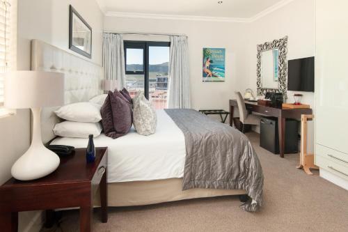 a bedroom with a large bed with a desk and a desk at Harbour House Hotel - Harbour Square in Hermanus